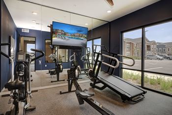 A gym with exercise equipment and a tv on the wall